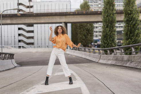 Unbekümmerte junge Frau tanzt auf einer Brücke in der Stadt - MEF00010