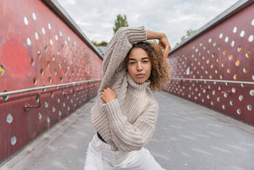 Young woman wearing sweater dancing while standing on bridge - MEF00015