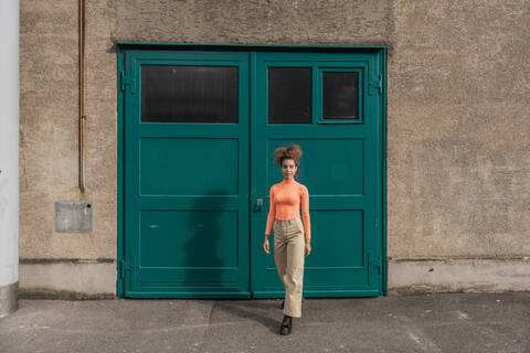 Young woman walking against green door stock photo
