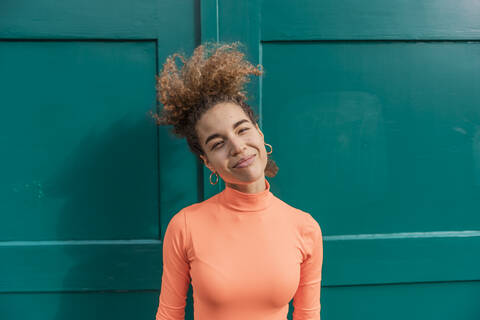 Smiling woman standing against green door stock photo