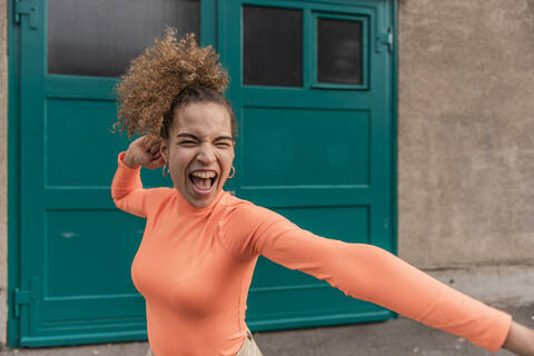 Cheerful woman dancing while standing against door stock photo