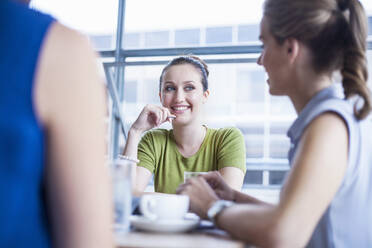 Smiling businesswoman looking at female colleague during meeting in office - AJOF00729