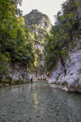 Man standing in Acheron River by mountain at Epirus, Greece - MAMF01458