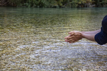 Mann beim Händewaschen im Fluss Acheron in Epirus, Griechenland - MAMF01463