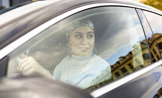 Junge Frau schaut beim Autofahren in der Stadt weg - JCCMF00067