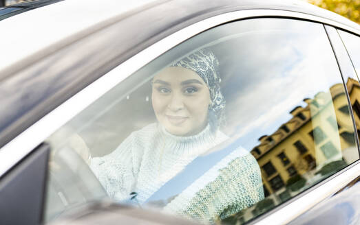 Junge Frau lächelt, während sie im Auto sitzt - JCCMF00068