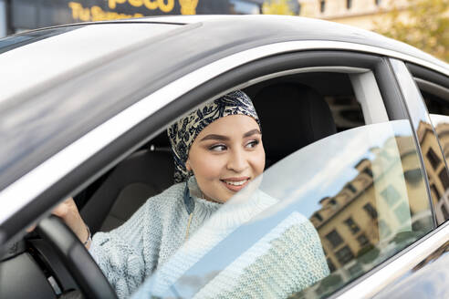 Lächelnde Frau, die wegschaut, während sie im Auto sitzt - JCCMF00069