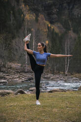 Junge flexible Frau bei einer Dehnungsübung am Fluss, Ordesa-Nationalpark, Huesca, Spanien - ACPF00942