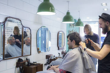 Friseure schneiden Kunden die Haare im Friseursalon - AJOF00749