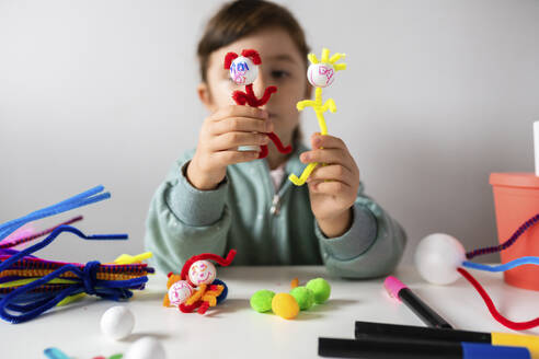 Mädchen spielt zu Hause mit kreativem Spielzeug aus Pfeifenreinigern und Pom-Pom - GEMF04419