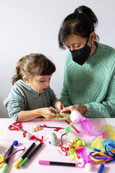 Großmutter und Enkelin basteln zu Hause während der Pandemie kreatives Spielzeug aus Pfeifenreinigern und Pom-Pom - GEMF04431