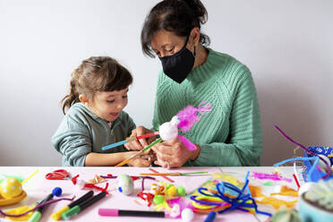 Großmutter und Enkelin basteln während COVID-19 kreatives Spielzeug aus Pfeifenreinigern und Pompons - GEMF04432