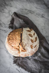 Draufsicht auf leckeres frisch gebackenes Brot mit knuspriger Kruste auf Marmortisch in moderner Küche - ADSF18444
