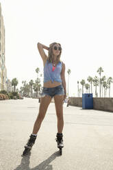 Junge Frau mit cooler Einstellung auf Inline-Skates auf der Promenade an einem sonnigen Tag - AJOF00761