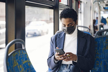 Young businesswoman using mobile phone in bus during COVID-19 - VYF00302