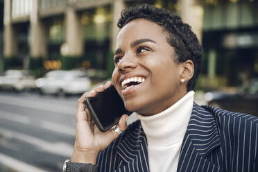 Happy young businesswoman looking away while talking on smart phone - VYF00334