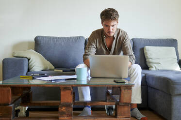 Geschäftsmann konzentriert sich bei der Arbeit am Laptop zu Hause - KIJF03391
