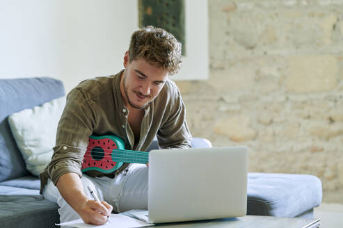 Mann lernt Ukulele über Laptop während eines Online-Tutorials zu Hause - KIJF03414