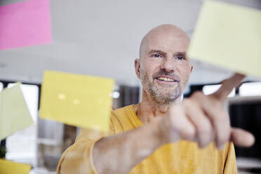 Mature man reading adhesive note - FMKF06803