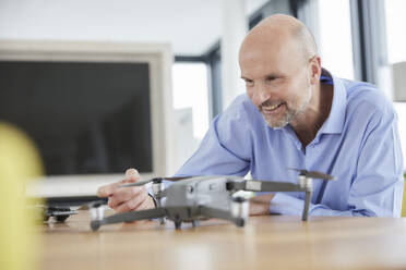 Geschäftsmann überprüft Quadcopter zu Hause - FMKF06819