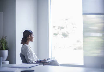 Young female entrepreneur sitting with document at office - AJOF00783