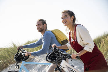 Couple with bicycles walking against clear sky - UUF22190