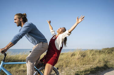 Man and woman enjoying bicycle ride against clear sky - UUF22206