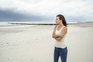 Junge Frau, die am Strand stehend die Aussicht betrachtet - UUF22249