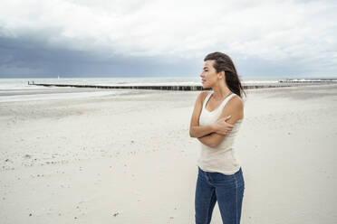 Young woman looking at view while standing at beach - UUF22249