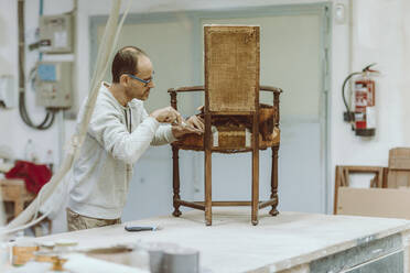 Fachwissen über die Restaurierung von Holzstühlen im Stehen in der Werkstatt - OCAF00553