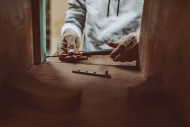 Handwerker zieht Schraube mit Schraubenzieher an, während er in der Werkstatt arbeitet - OCAF00562