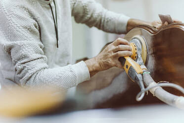 Expertise polishing furniture with sander while working at workshop - OCAF00580