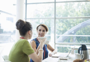 Businesswoman having meeting with colleague while drinking coffee at office - AJOF00811