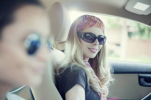 Lächelnde Frau mit ihrer Freundin im Auto während einer Autoreise - AJOF00818