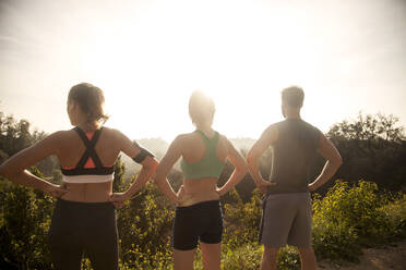 Athletes looking at view while standing with hand on hip outdoors - AJOF00850