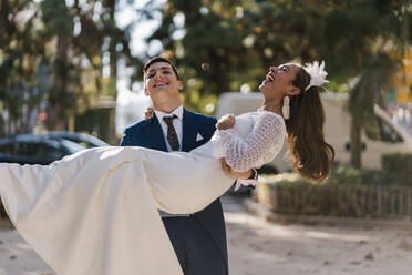 Junger Bräutigam holt fröhliche Braut im Park ab - EGAF01167