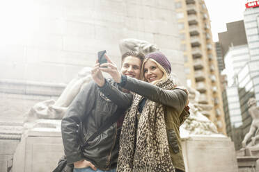 Junge Frau nimmt Selfie mit Mann durch Handy, während in der Stadt stehen - AJOF00879