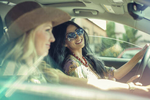 Schöne junge Frau schaut ihre Freundin an, während sie Auto fährt - AJOF00917