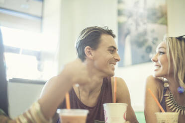 Fröhlicher Mann und Frau schauen sich an, während sie in einem Café Kaffee trinken - AJOF00942