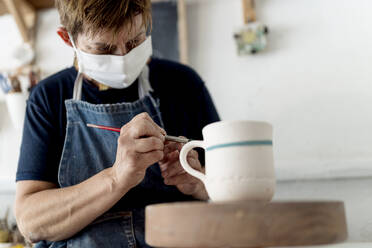 Künstlerin bemalt Tasse in Keramikwerkstatt - EGAF01178