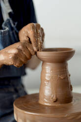 Ältere Töpferin formt Ton auf der Töpferscheibe in einer Keramikwerkstatt - EGAF01183