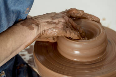 Ältere Töpferin bei der Herstellung von Töpferwaren auf der Drehscheibe in einer Keramikwerkstatt - EGAF01186
