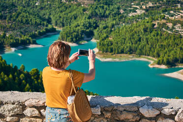 Frau nimmt ein Bild mit seinem Telefon von einem See in Guadalest - CAVF91301