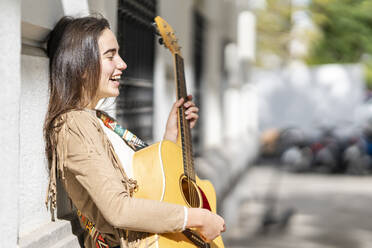 Musikerin lacht beim Gitarrenspiel in der Stadt - GGGF00266