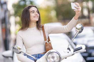 Frau mit Motorroller nimmt Selfie auf Smartphone - GGGF00280