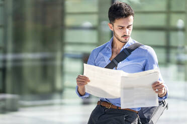 Businessman reading newspaper while sitting outdoors - GGGF00345