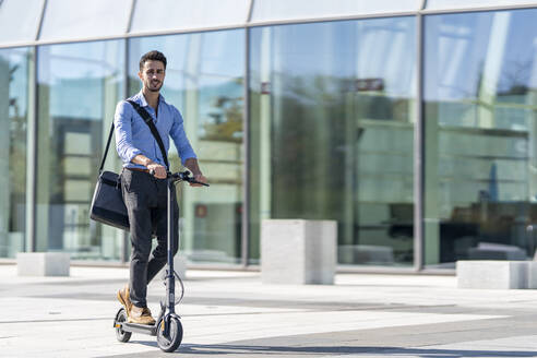 Geschäftsmann fährt mit einem elektrischen Roller auf dem Gehweg - GGGF00357