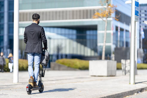 Geschäftsmann fährt auf dem Gehweg mit einem Motorroller - GGGF00384