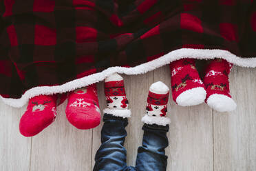 Eltern und kleiner Junge tragen Weihnachtssocken zu Hause während der Weihnachtszeit - EBBF01693