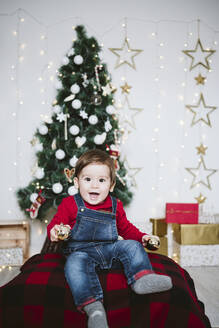 Fröhlicher kleiner Junge mit offenem Mund, der zu Hause während der Weihnachtszeit spielt - EBBF01698